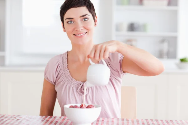 Woman pouring cream over strawberries looking into the camera — Stock Photo, Image