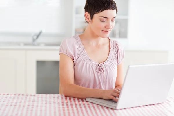 Bir dizüstü bilgisayar ile çalışan büyüleyici kadın — Stok fotoğraf