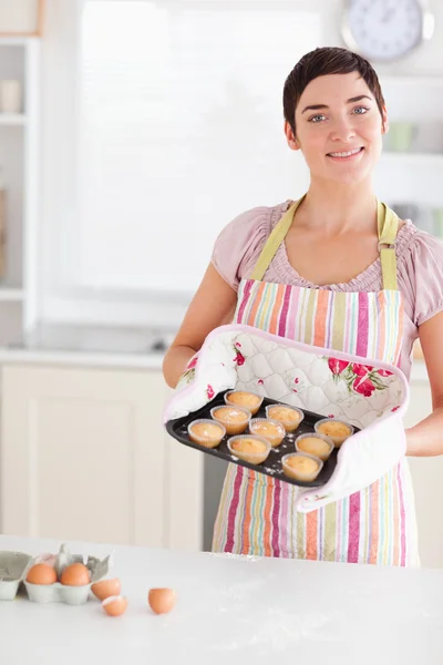 Mulher morena bonita mostrando muffins — Fotografia de Stock