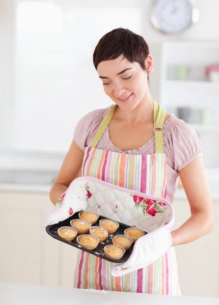 Lachende brunette vrouw tonen muffins — Stockfoto