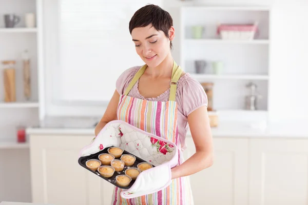 Charming brunette woman showing muffins — Stock Photo, Image