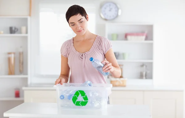 Mulher colocando garrafas em uma caixa de reciclagem — Fotografia de Stock