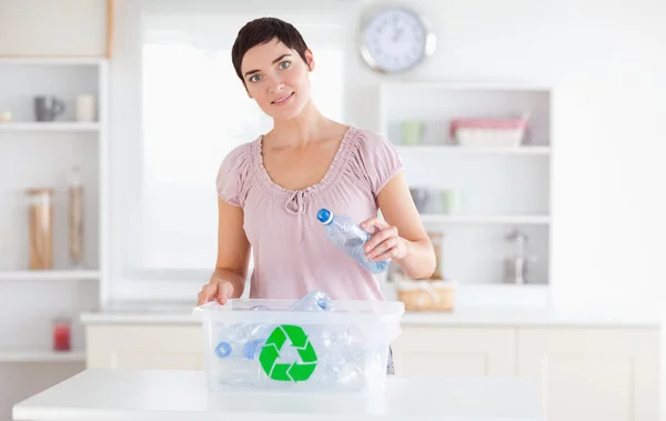 Leuke vrouw die flessen in een recyclingdoos doet — Stockfoto
