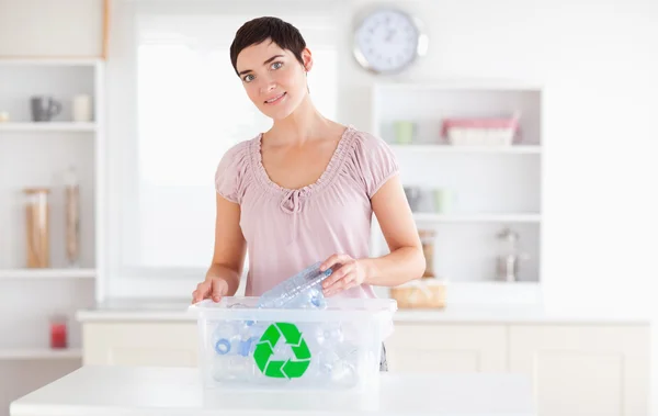Sorrindo Mulher colocando garrafas em uma caixa de reciclagem — Fotografia de Stock