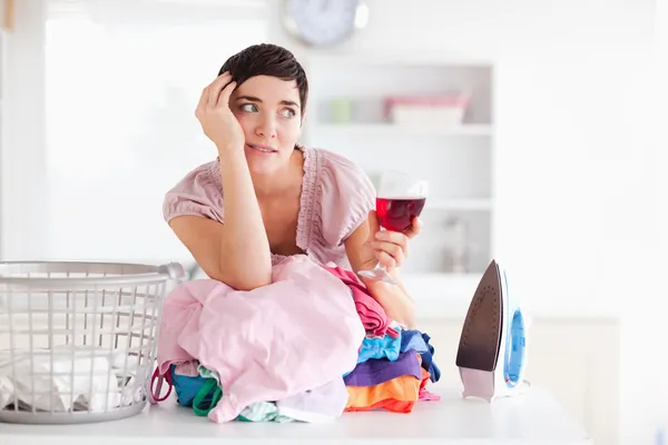 Upset woman with wine and a pile of clothes — Stock Photo, Image