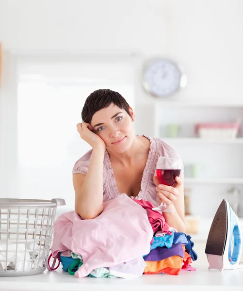 Brunette Woman with wine and a pile of clothes — Stock Photo, Image