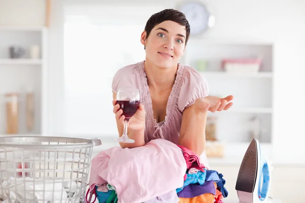 Beautiful Woman with wine and a pile of clothes — Stock Photo, Image