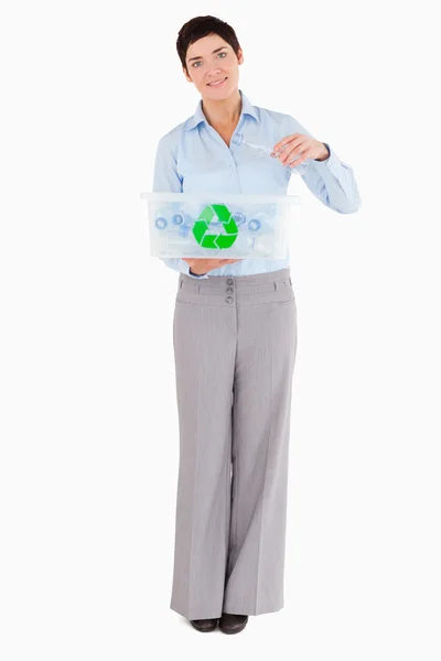 Mulher colocando uma garrafa de plástico em uma caixa de reciclagem — Fotografia de Stock