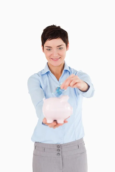 Mulher colocando uma nota bancária em um banco porquinho — Fotografia de Stock