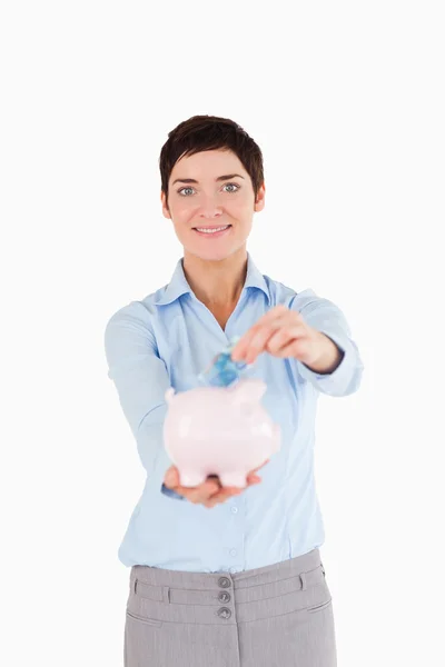 Businesswoman putting a bank note in a piggy bank — Stock Photo, Image