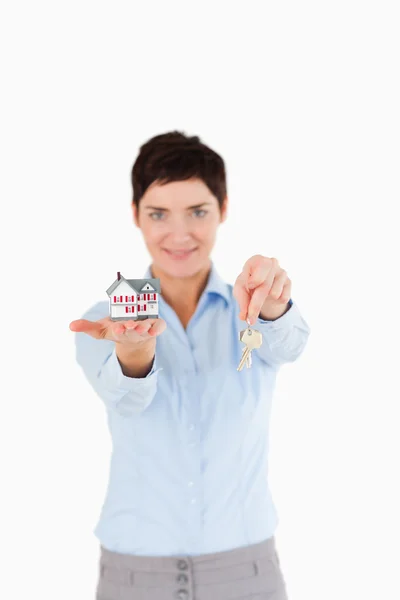 Kvinnan visar nycklar och en miniatyr hus — Stockfoto