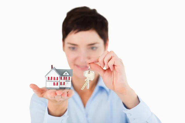 Close up of a businesswoman showing keys and a miniature house — Stock Photo, Image
