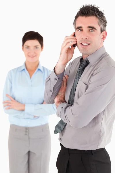 Retrato de um homem fazendo um telefonema enquanto seu colega é pos — Fotografia de Stock