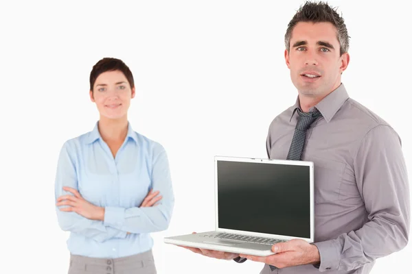 Kontorist visar en laptop medan hans kollega poserar — Stockfoto