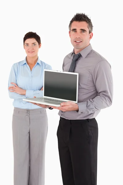 Retrato de um homem mostrando um laptop enquanto seu colega está posando — Fotografia de Stock