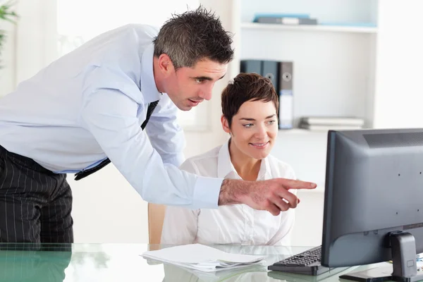 Businessman pointing at something on a screen to his secretary — Stock Photo, Image