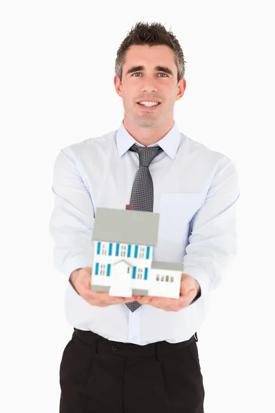 Агент по недвижимости держит миниатюрный дом — стоковое фото