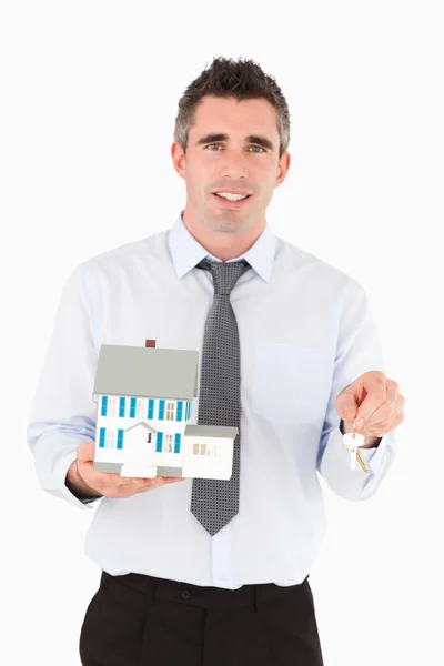 Man holding a key and a miniature house — Stock Photo, Image