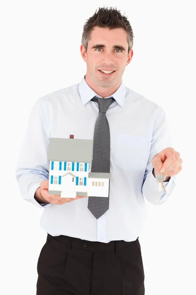 Podnikatel drží klíč a miniaturní dům — Stock fotografie