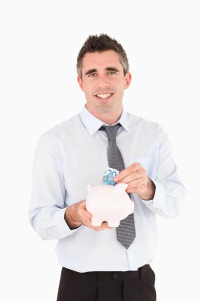 Mann legt Geldschein in Sparschwein — Stockfoto