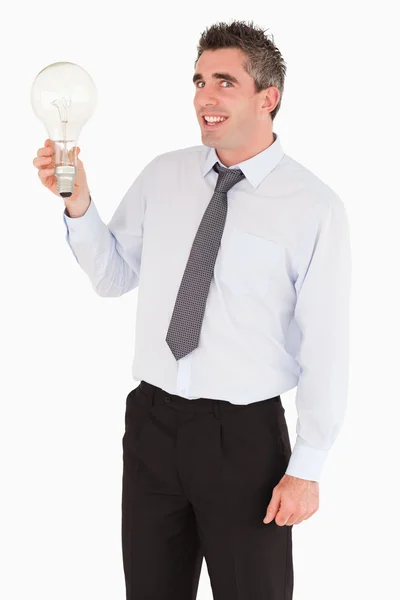 Uomo sorridente che tiene una lampadina — Foto Stock