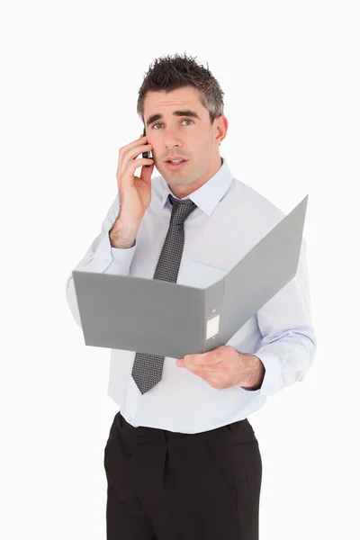 Portrait of a man making a phone call while holding a binder — Stock Photo, Image