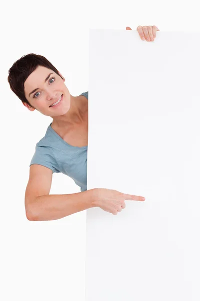 Morena sorridente apontando para um painel em branco — Fotografia de Stock