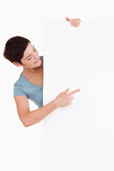 Smiling brunette looking at a blank panel — Stock Photo, Image