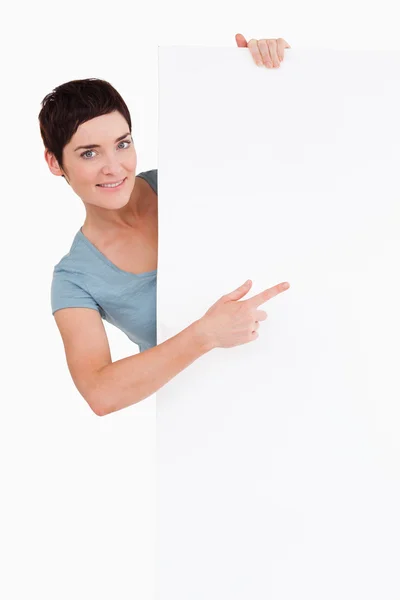 Linda morena apontando para um painel em branco — Fotografia de Stock