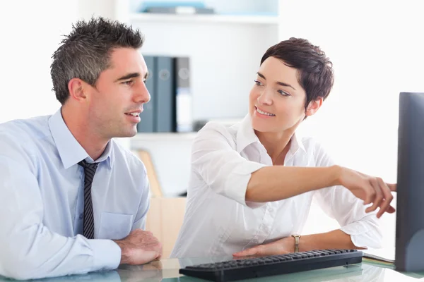Office worker pointing a something on a screen to her colleague — Stock Photo, Image