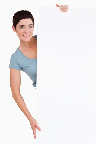 Mulher posando atrás de um painel em branco — Fotografia de Stock