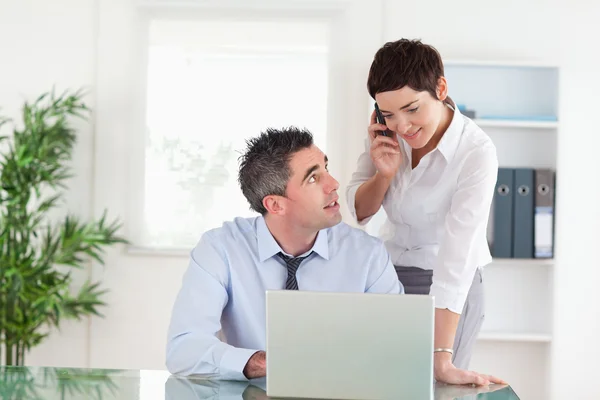 Empresaria haciendo una llamada telefónica mientras su colega está trabajando —  Fotos de Stock