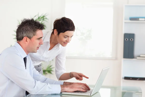 Женщина указывает на что-то своему коллеге на ноутбуке — стоковое фото