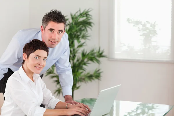 Manager en zijn secretaresse poseren met een laptop — Stockfoto