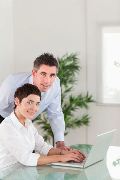 Porträtt av en chef och hans sekreterare som poserar med en bärbar dator — Stockfoto