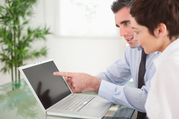 Manager wijst op iets naar zijn secretaresse op een laptop — Stockfoto