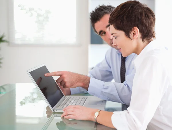 Man pointing at something to his secretary on a laptop — Stock Photo, Image