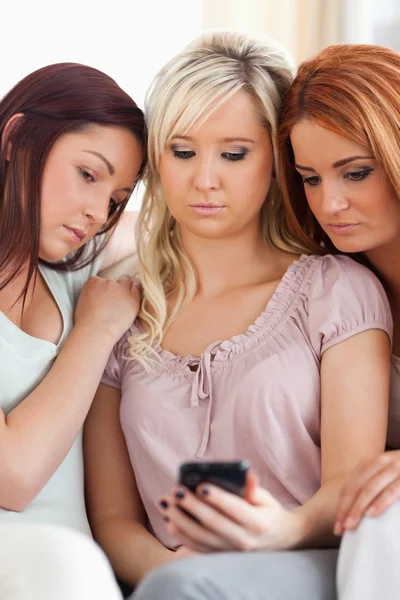 Leuke vrienden zittend op een bank met een mobiele telefoon — Stockfoto