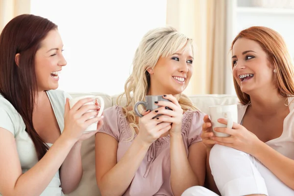 Jublande kvinnor sitter på en soffa med koppar — Stockfoto