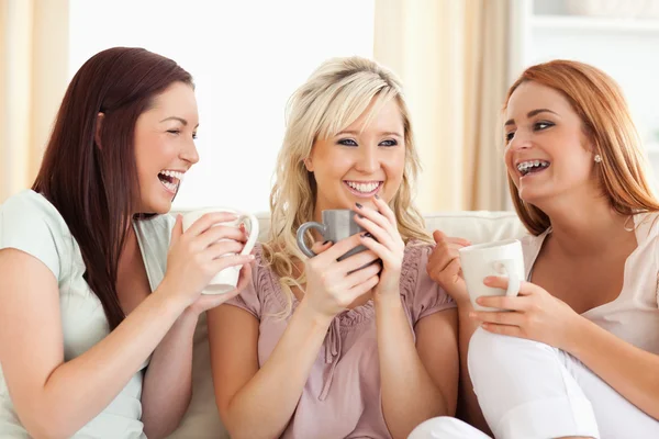 Mulheres alegres sentadas em um sofá com copos — Fotografia de Stock