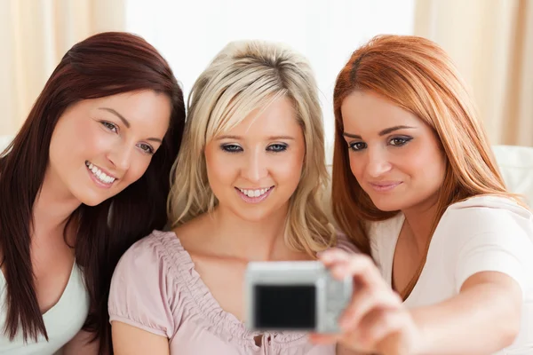 Vrouwen die loungen op een bank met een camera glimlachen — Stockfoto