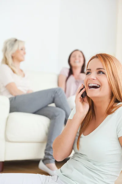 Laughing woman with a cellphone separated from the others — Stock Photo, Image