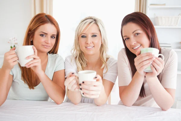 Cute vrouwen zitten aan een tafel met cups — Stockfoto