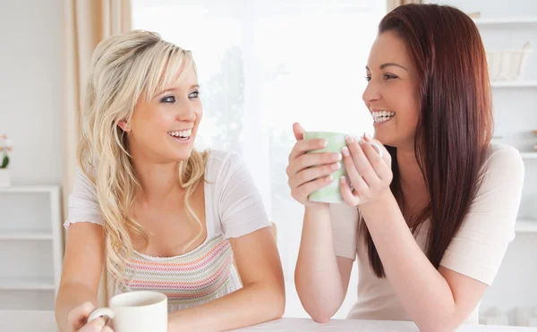 Smějící se ženy sedí u stolu s cups — Stock fotografie