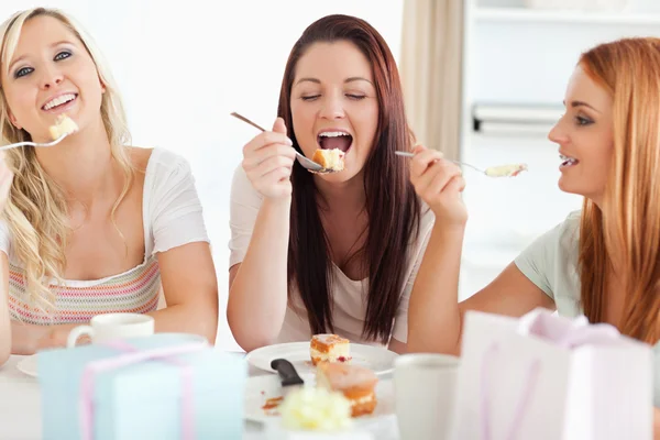 Mulheres bonitas sentadas em uma mesa comendo um bolo — Fotografia de Stock