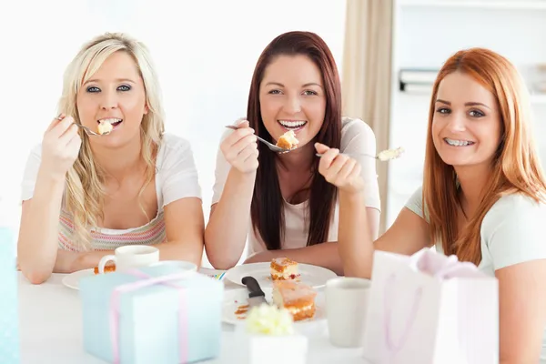 Wunderschöne Frauen sitzen an einem Tisch und essen einen Kuchen — Stockfoto