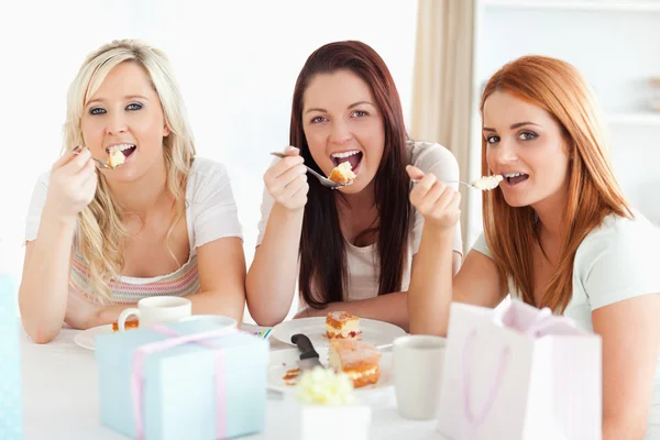 Gut aussehende Frauen, die an einem Tisch sitzen und einen Kuchen essen — Stockfoto