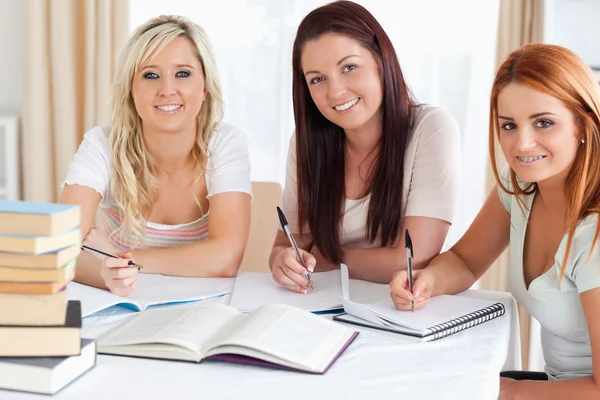 Обаятельные женщины, сидящие за столом и учащиеся — стоковое фото