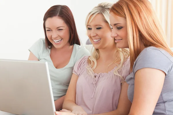 Donne sorridenti sedute su un divano con un computer portatile — Foto Stock