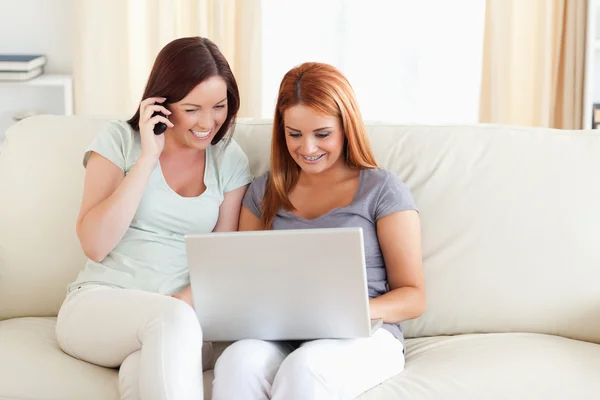Mujeres sentadas en un sofá con un portátil y un teléfono —  Fotos de Stock